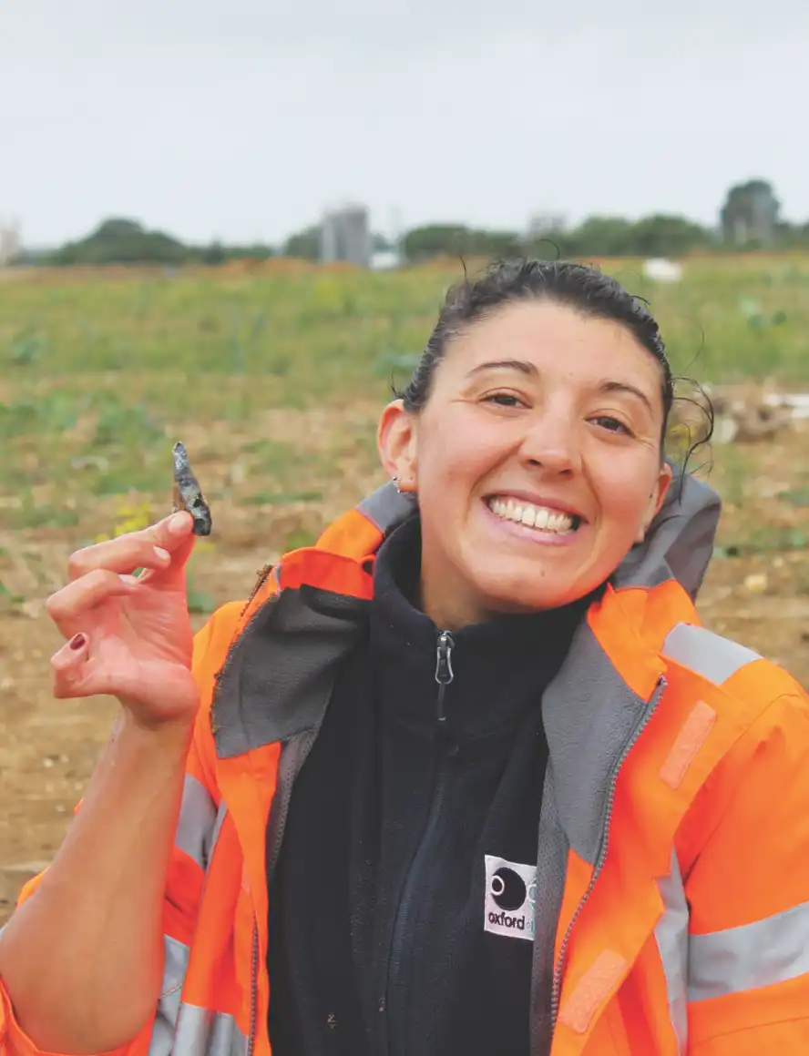 An archaeologist in the field holding a flint