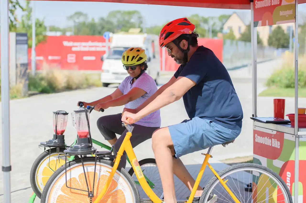 Two adults on bicycles that are powering food blenders