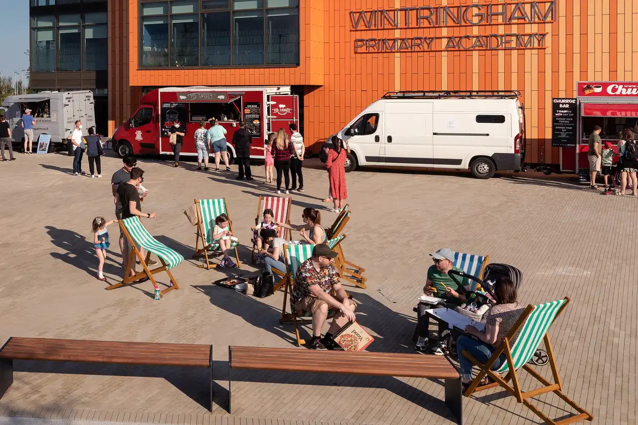 People sitting outside in deckchairs with food vans in the background