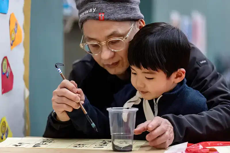 Young boy being shown Chinese brush writing