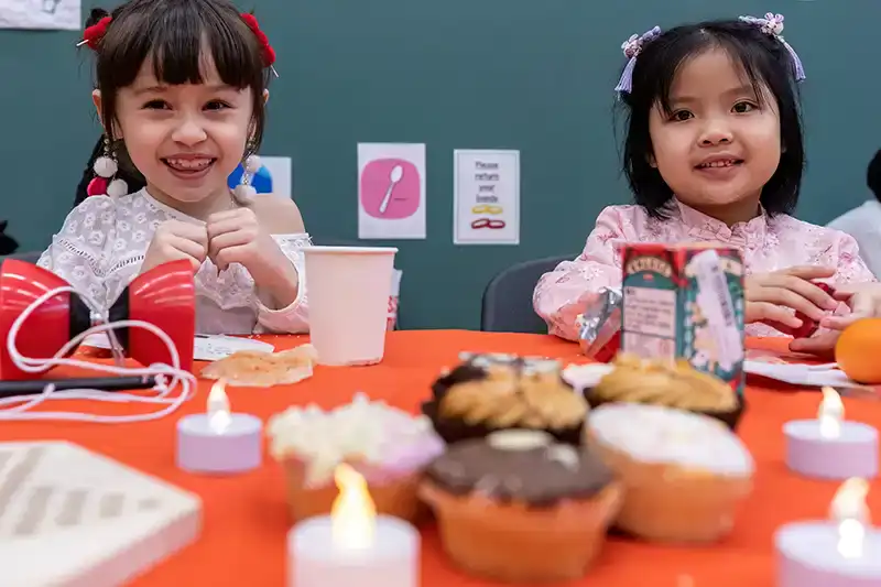 Two girls smiling, sitting at table of food