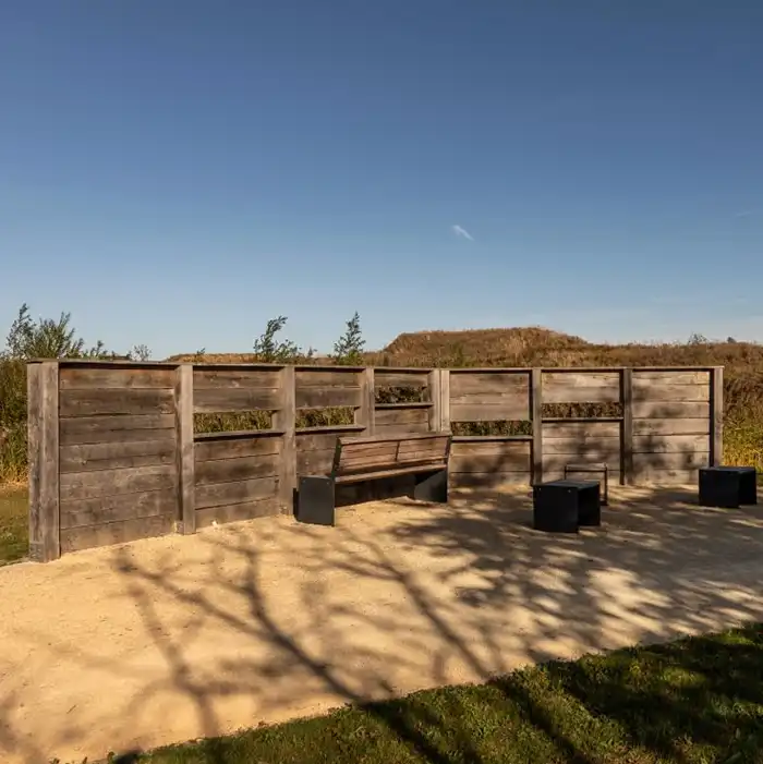 Wooden bird hide with bench seating overlooking open ground within the development