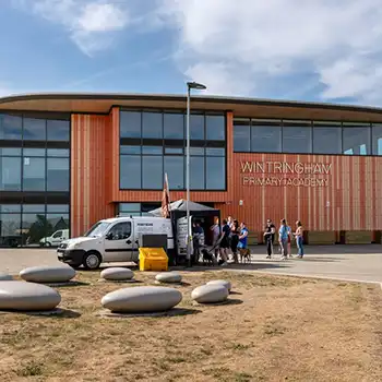 Wintringham Primary Academy, a modern school building with orange cladding and curved glass frontage