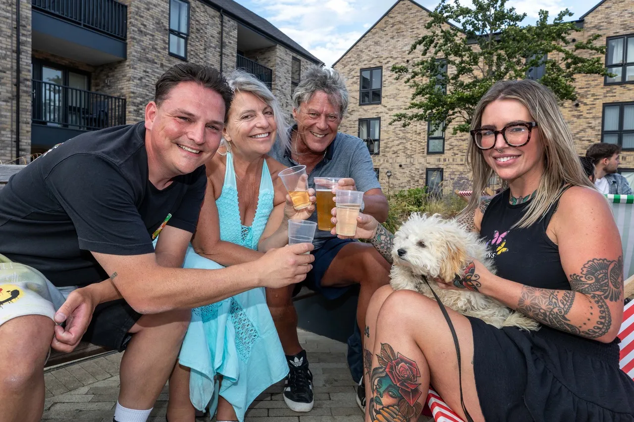 group of friends and a small dog toast drinks together while Wintringham enjoys taste of summer at pop-up street food event.